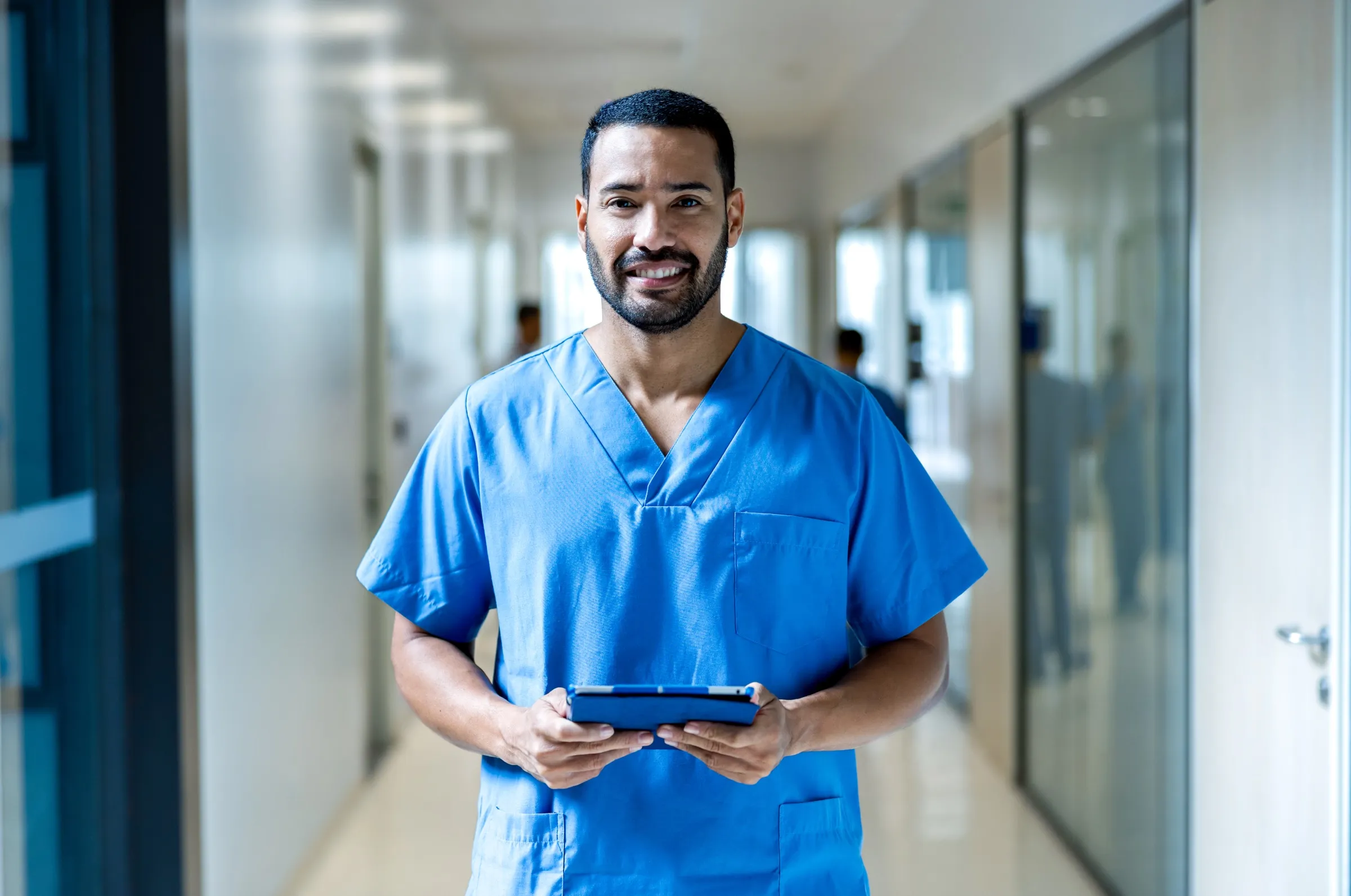 Nurse reviewing a chart on a tablet in a hospital corridor