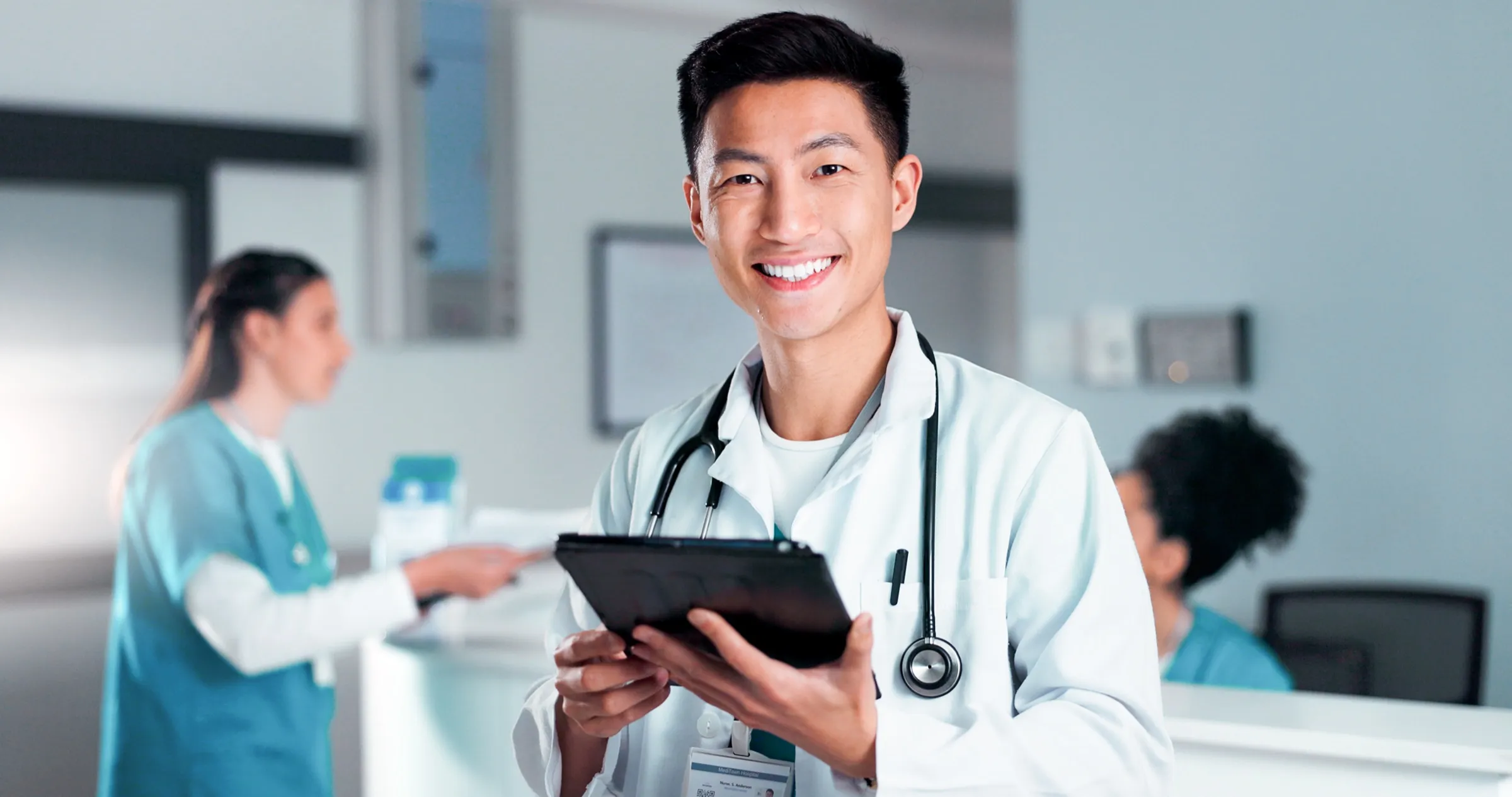 Physician reviewing patient notes on a tablet at a nurses station