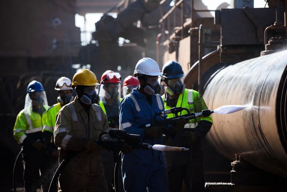 Industrial cleaning team using high pressure water jetting equipment on heavy machinery in South Africa