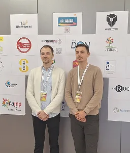 Deux hommes debout devant un mur couvert de logos d'entreprises et d'organisations.