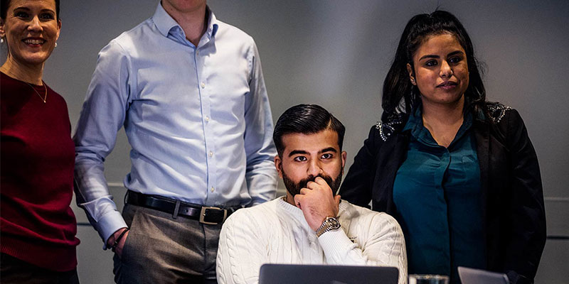 Fyra personer i möte med laptopskärmar i förgrunden