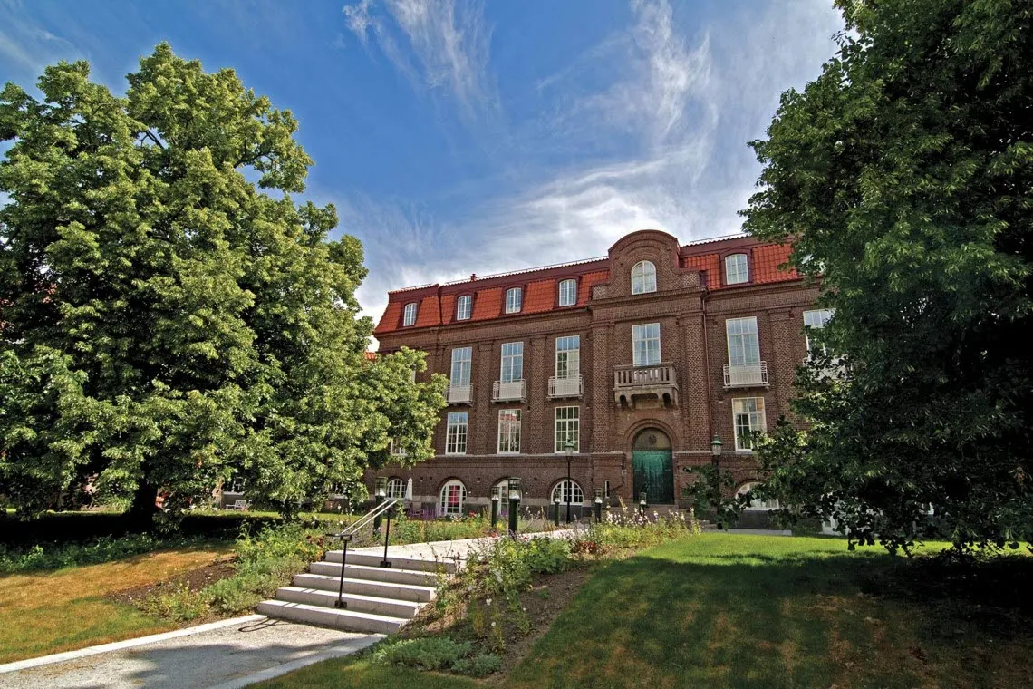 Ribbingska huset i Lund, fotografi på fasad med träd och parkmiljö i förgrunden