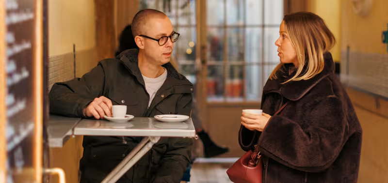     Två personer har ett samtal vid ett cafébord.