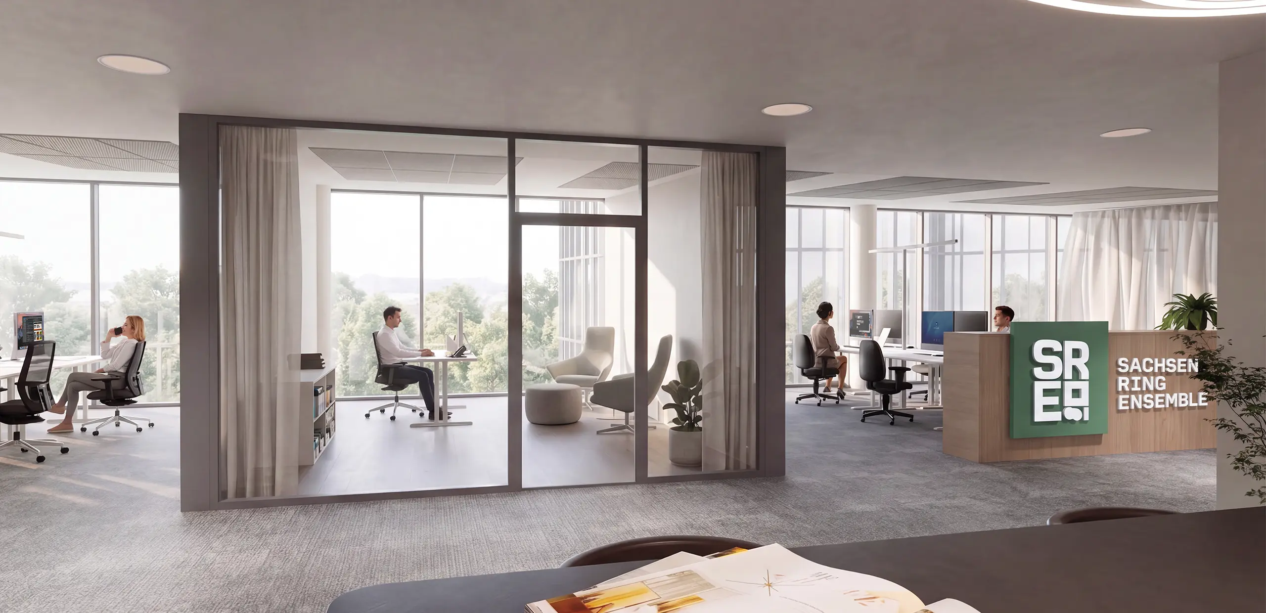 Modern office space with glass-walled private office where a man works at a desk, open-plan workstations with seated employees, and a wooden reception desk with 'Sachsenring Ensemble' sign.