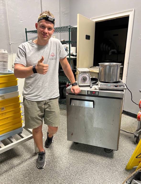 Technician standing next to a stainless steel kitchen appliance