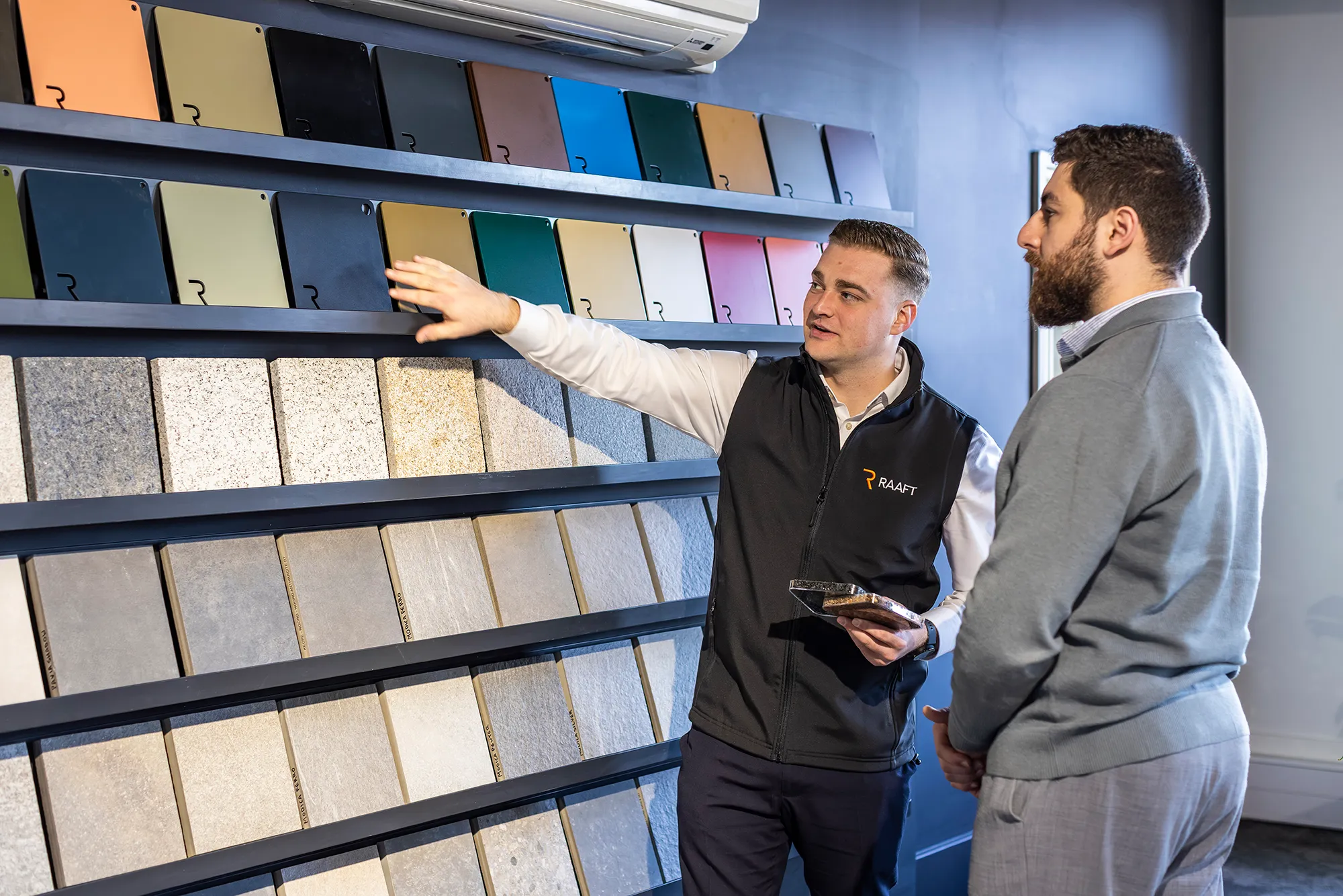 Salesman showing a customer various tile and color samples on display shelves in a showroom.
