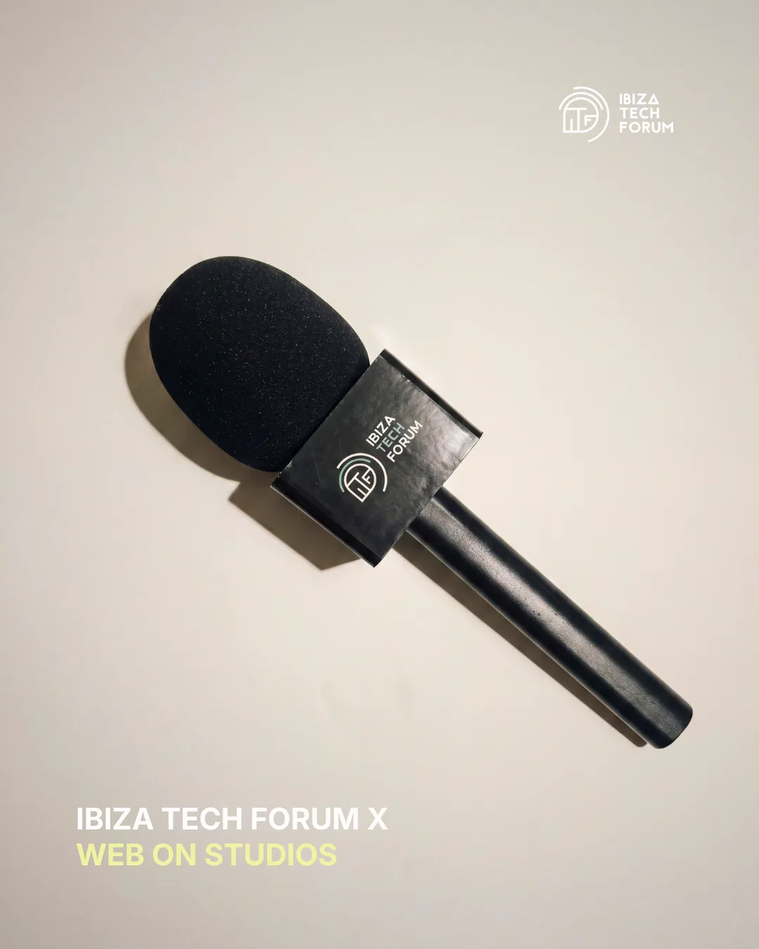 Micrófono con el logo de Ibiza Tech Forum sobre fondo arena