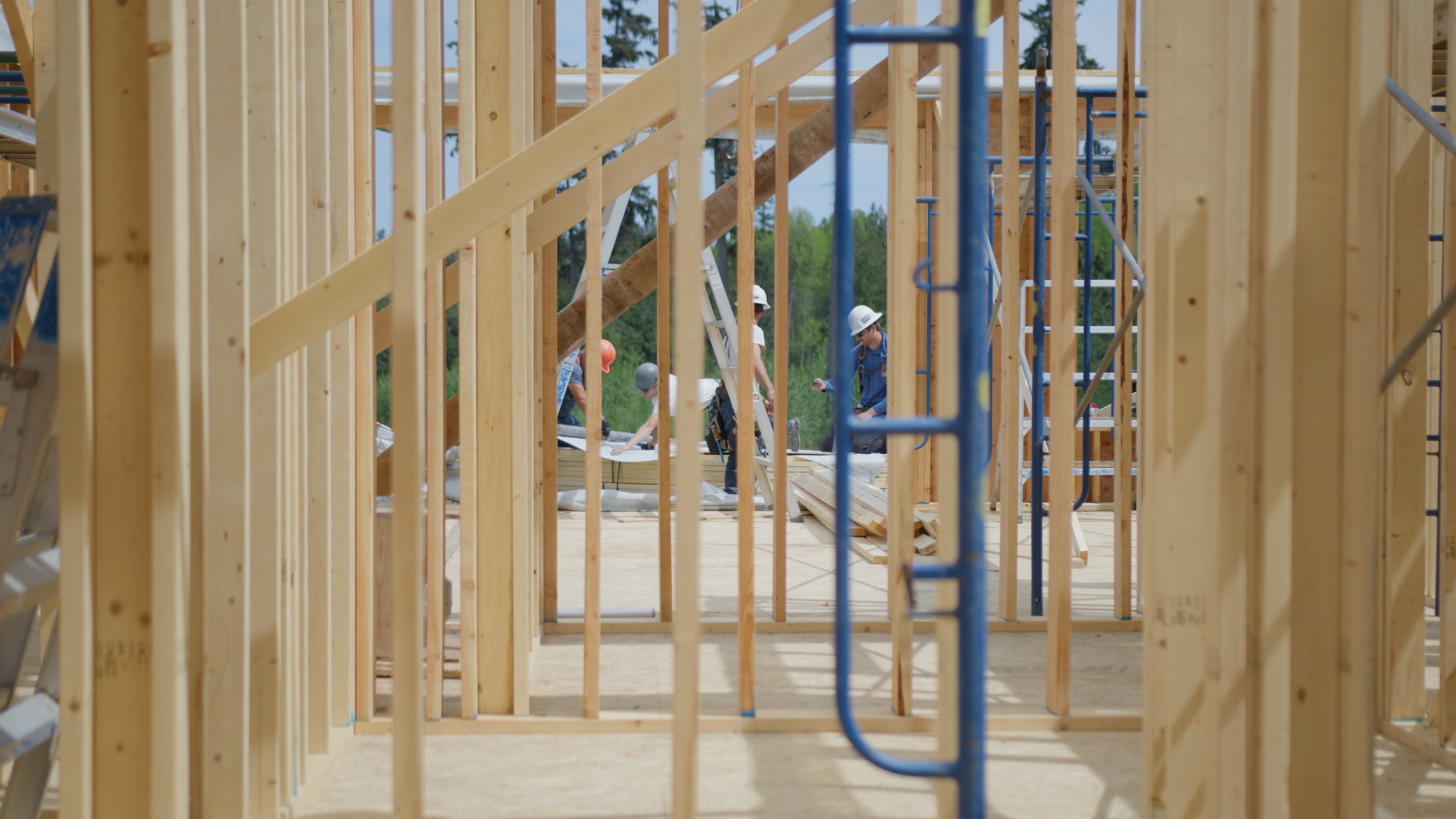 Don May Construction crew framing a new home, seen through the wall studs