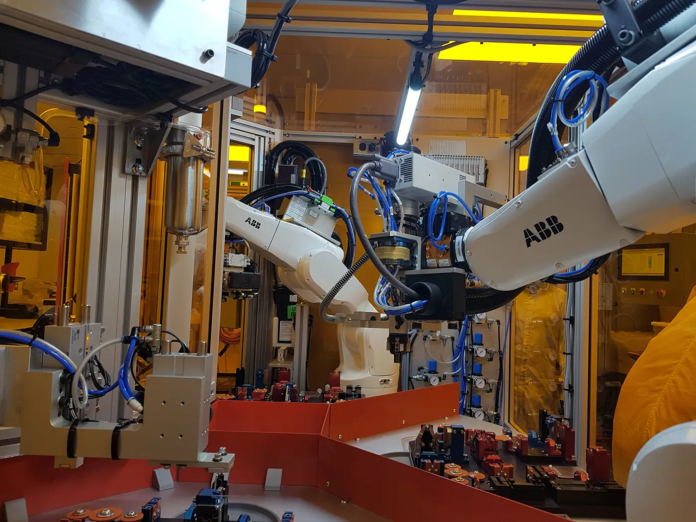 ABB robotic arms inside an enclosed automated manufacturing cell.