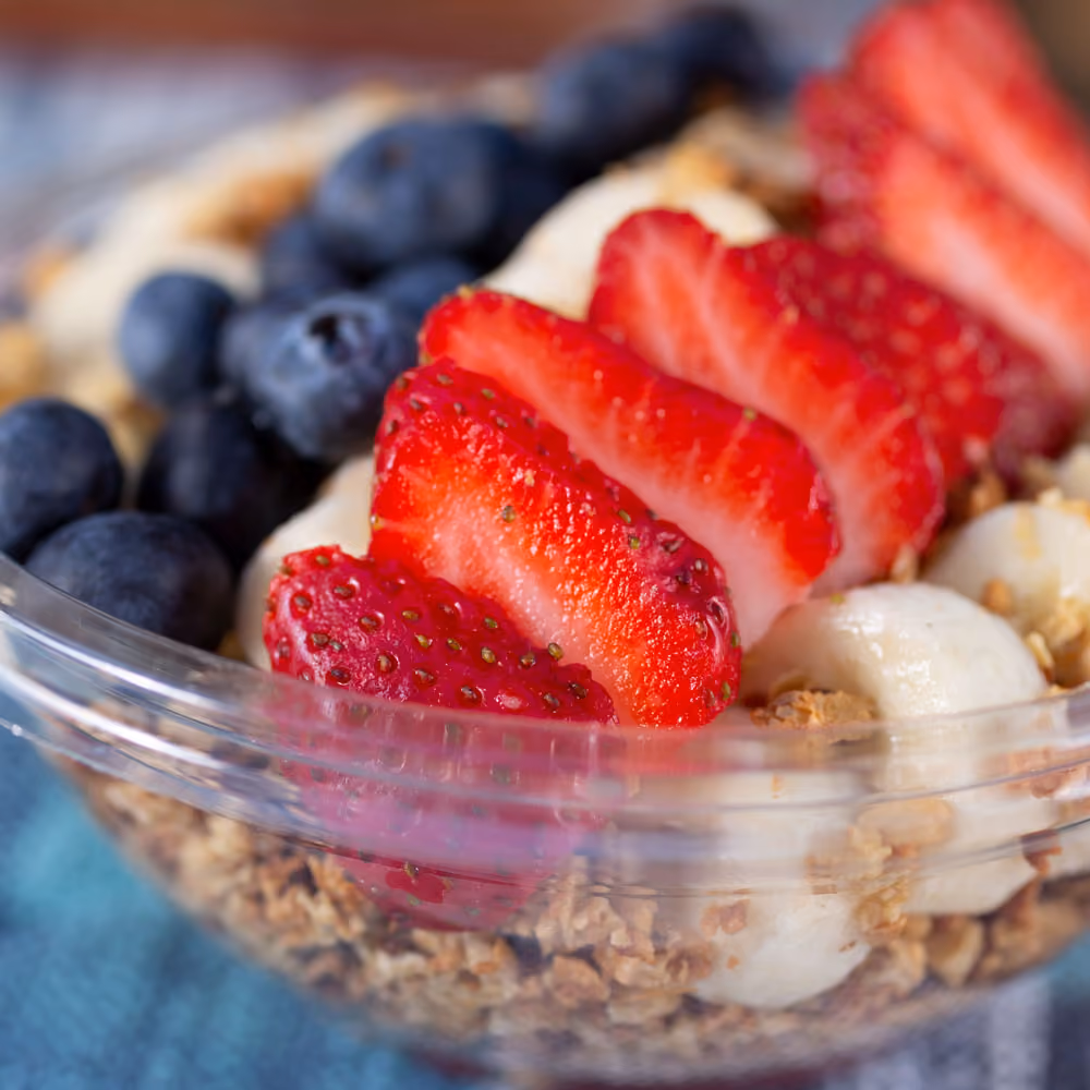 A bowl of fruit with strawberries, blueberries, and bananas.