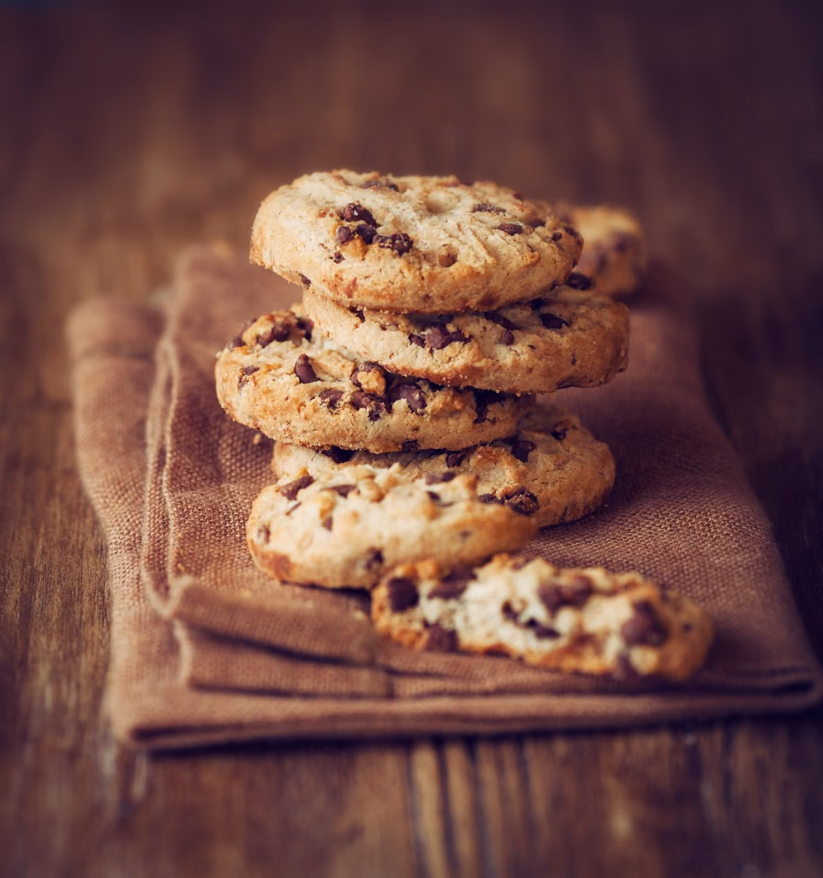 A stack of chocolate chip cookies on a brown napkin.