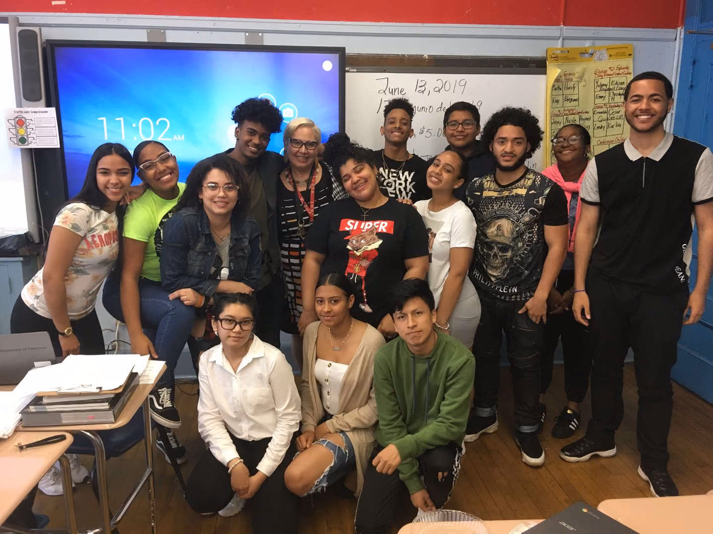 Teacher and high school students posing together in a classroom