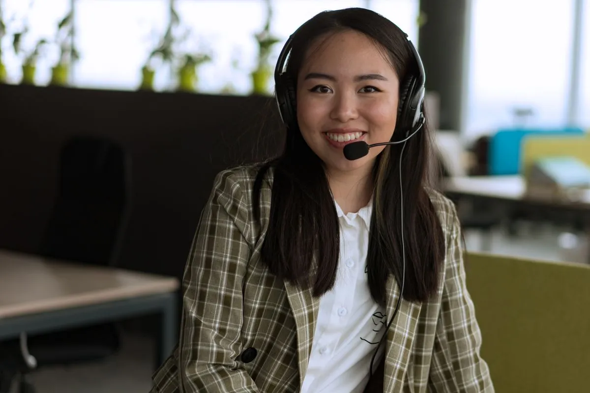 Une conseillère du service client, casque sur les oreilles, sourit