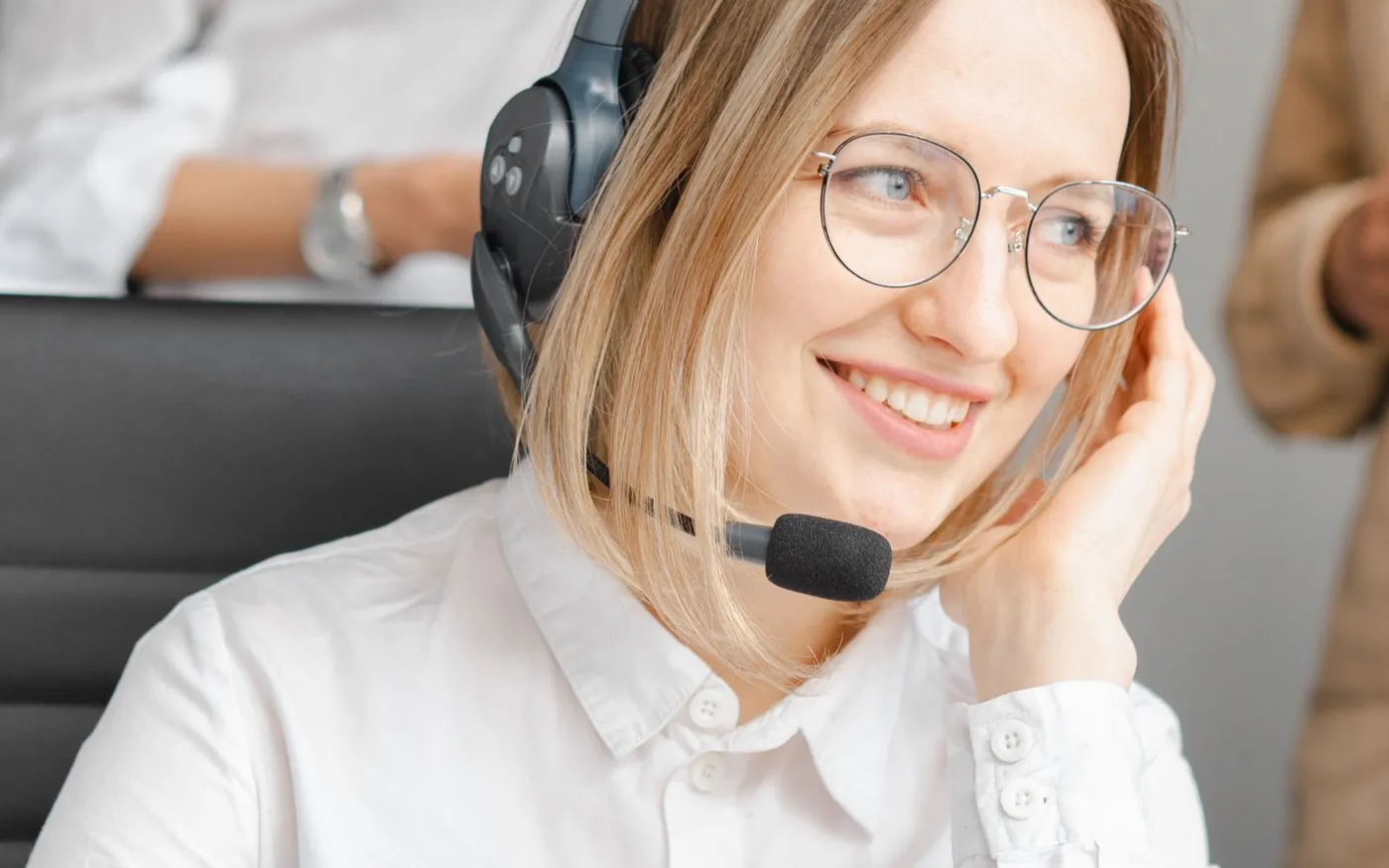 Une conseillère à lunettes, casque sur les oreilles, sourit