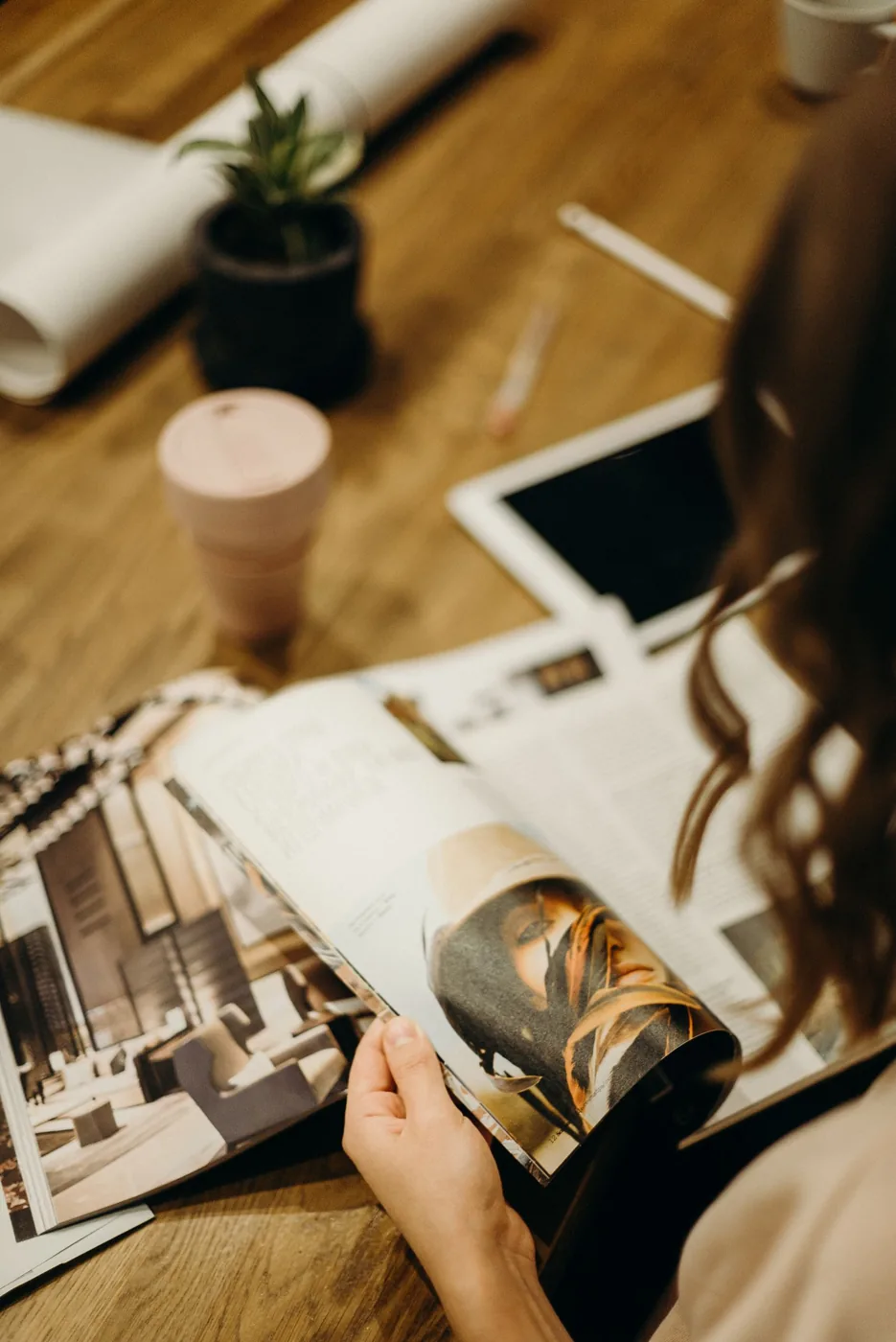 Une femme feuillette un magazine de mode posé sur une table en bois