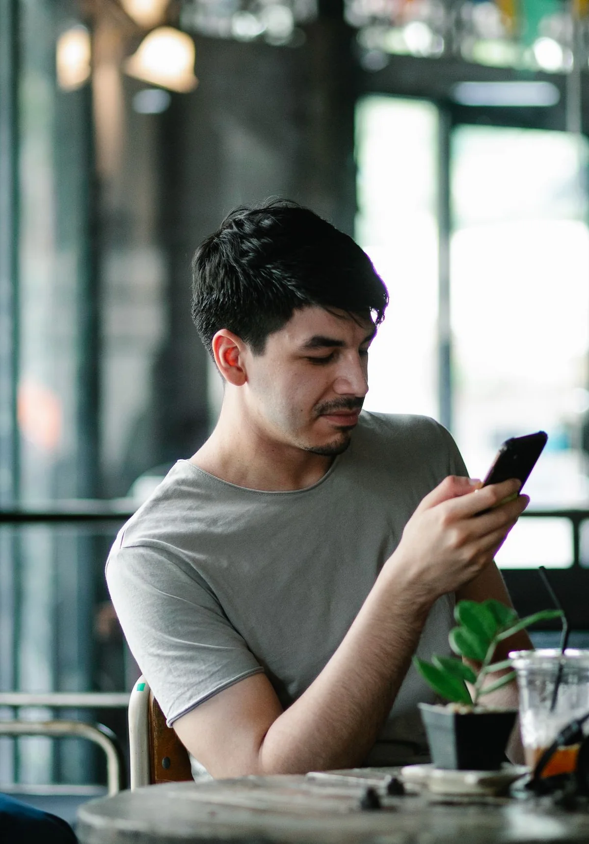 Un client lit la réponse reçue sur son téléphone, attablé dans un café