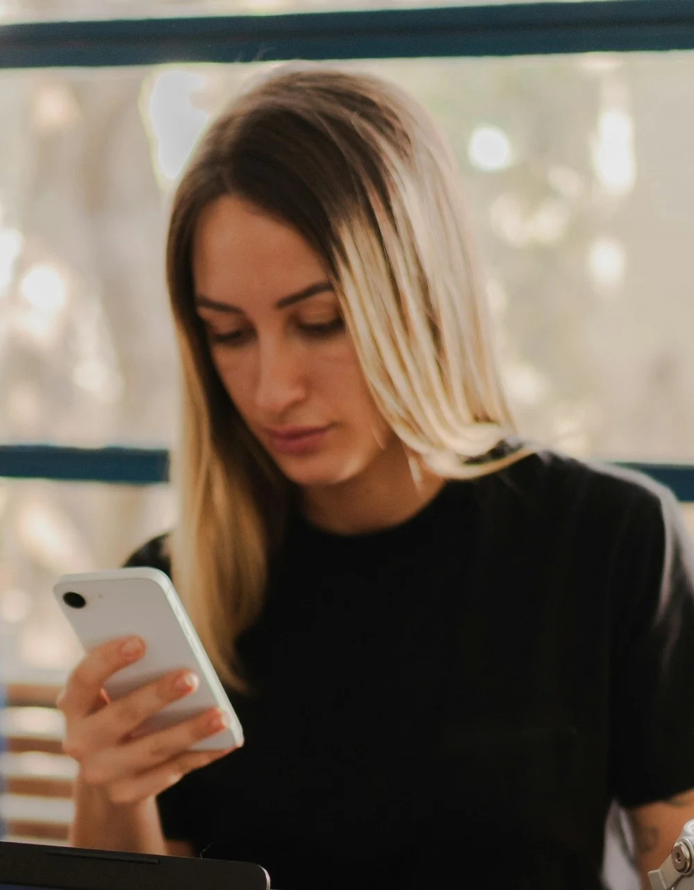 Une personne lit un message sur son téléphone, à son bureau