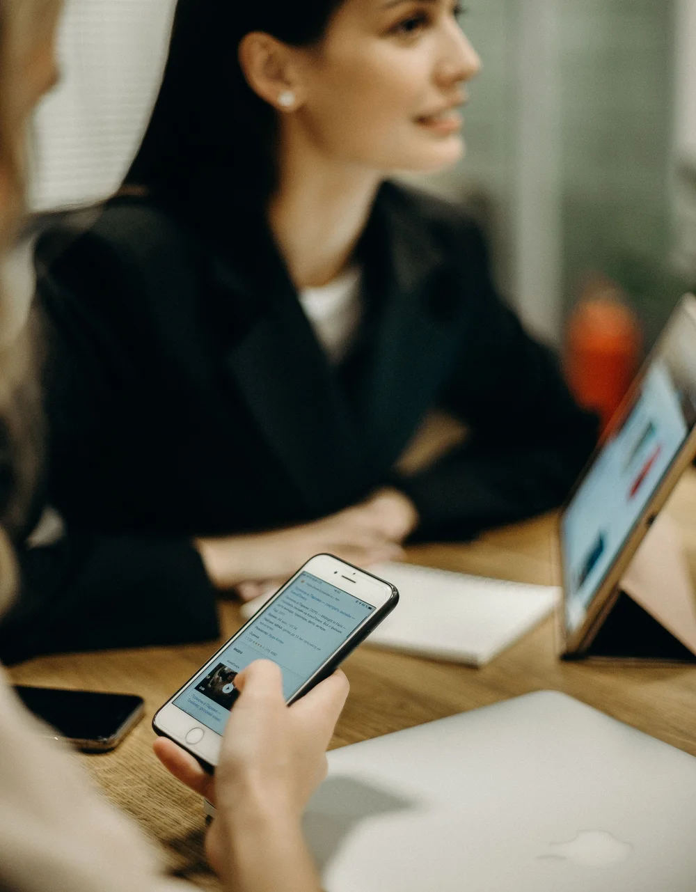 Deux personnes en réunion, l'une consulte une conversation sur son smartphone