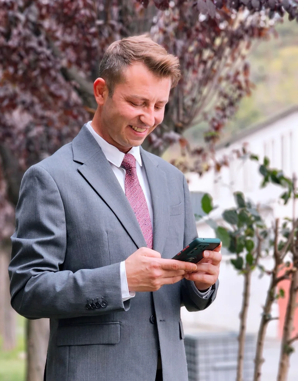 Un commercial en costume sourit en lisant un message sur son smartphone