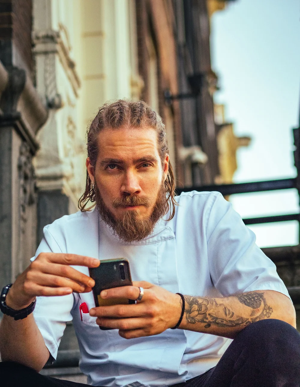 Un chef cuisinier en veste blanche tient son smartphone