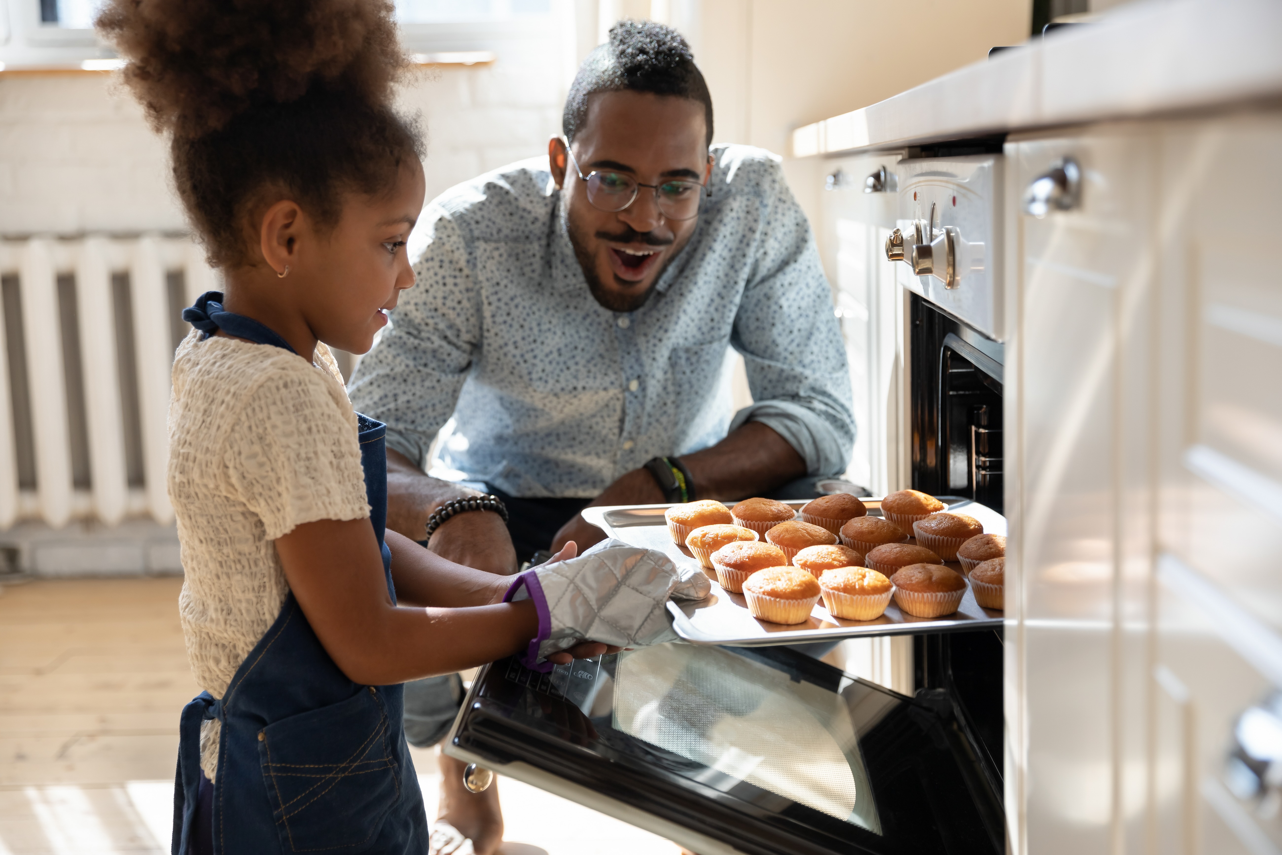 Girl taking muffins out of oven stock image