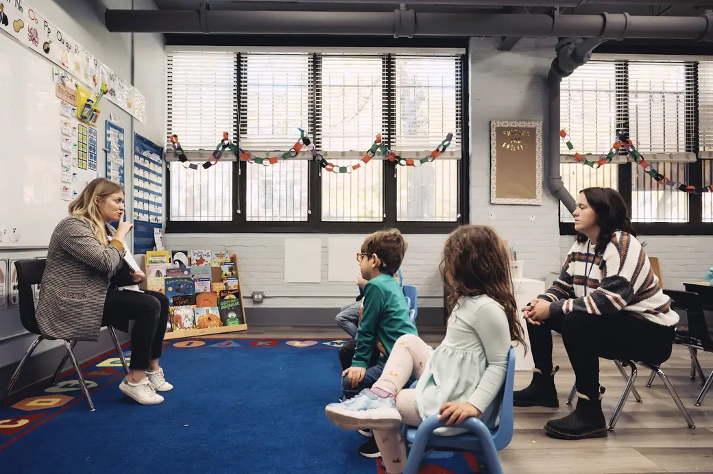 Morning meeting at Black Bear Academy: two teachers and a small group of children sit in a circle in a bright classroom