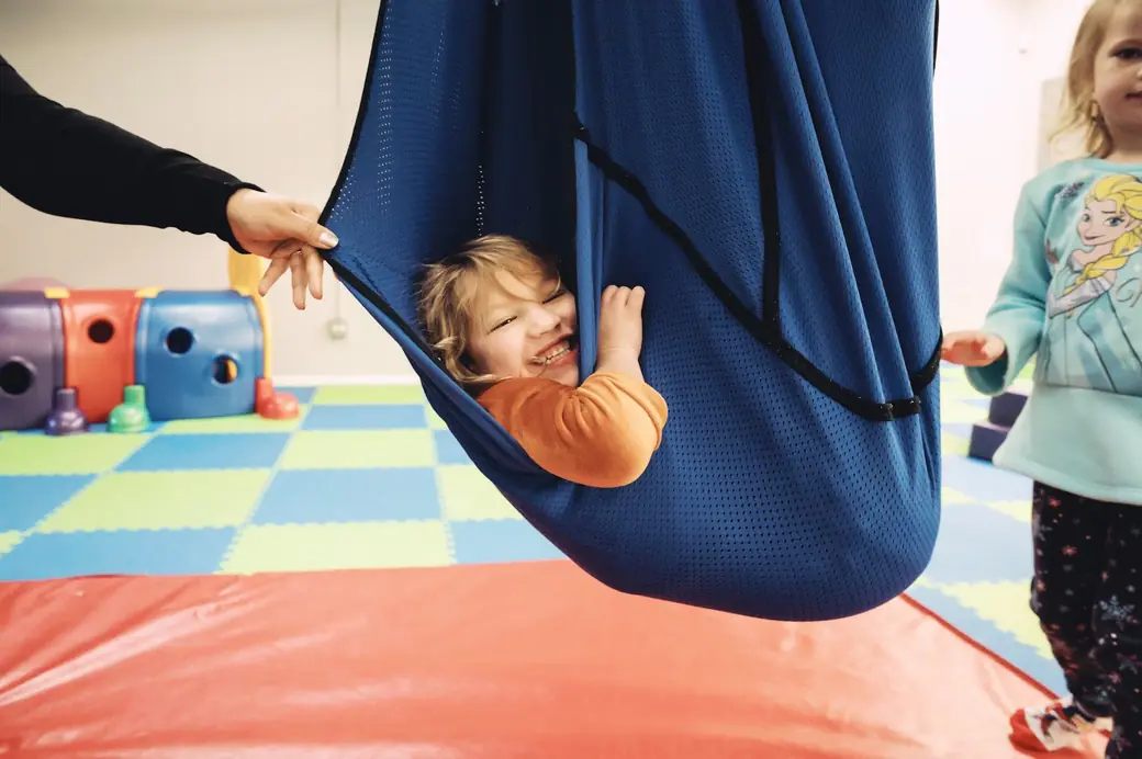 A child on the swing in the Black Bear Academy sensory gym during occupational therapy