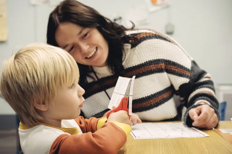 A Black Bear Academy staff member works one to one with a student at a table