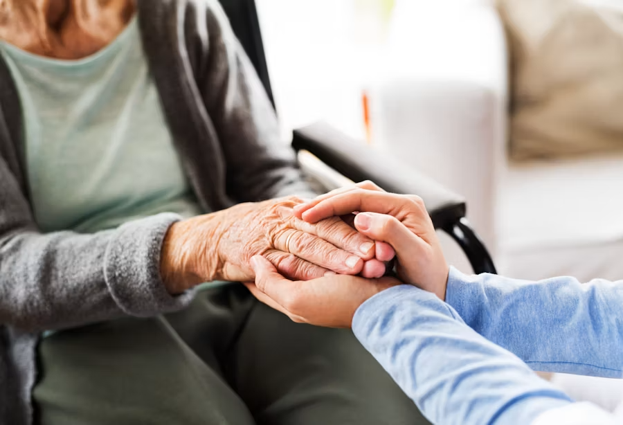 A caregiver from All in All Residential Services holding hands with a resident