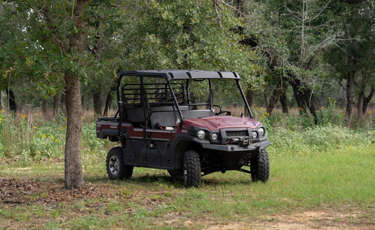 Red and black utility terrain vehicle parked in forest surrounded by green trees