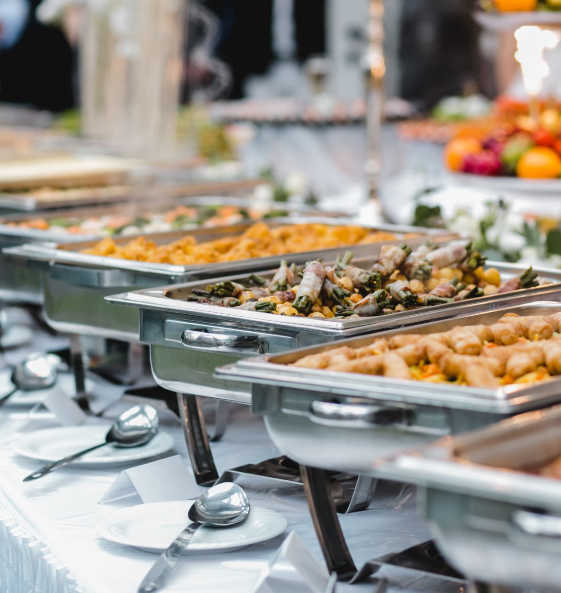 Buffet table with multiple chafing dishes of food and place settings at event