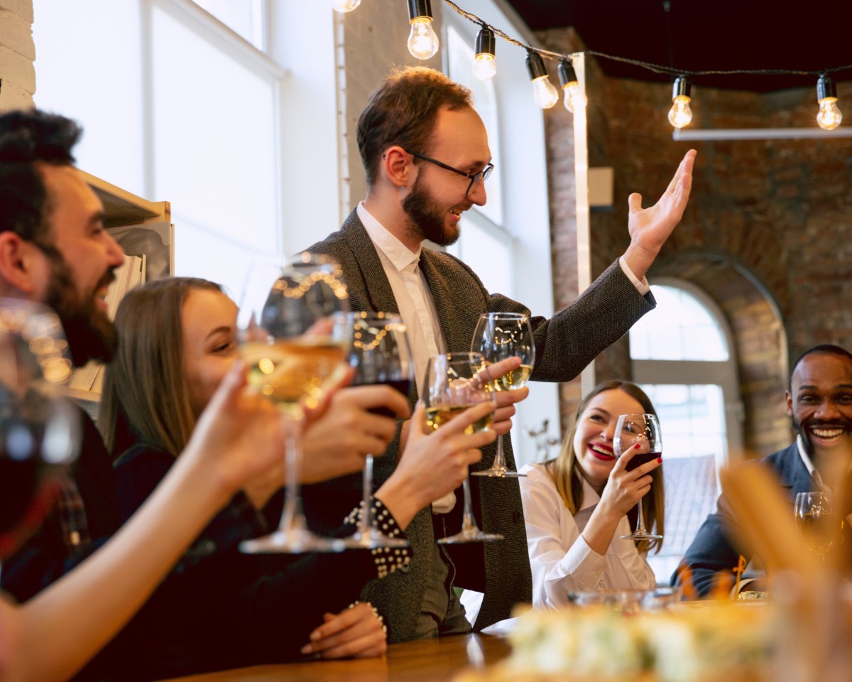 Family and friends toasting with wine glasses at elegant celebration dinner party indoors