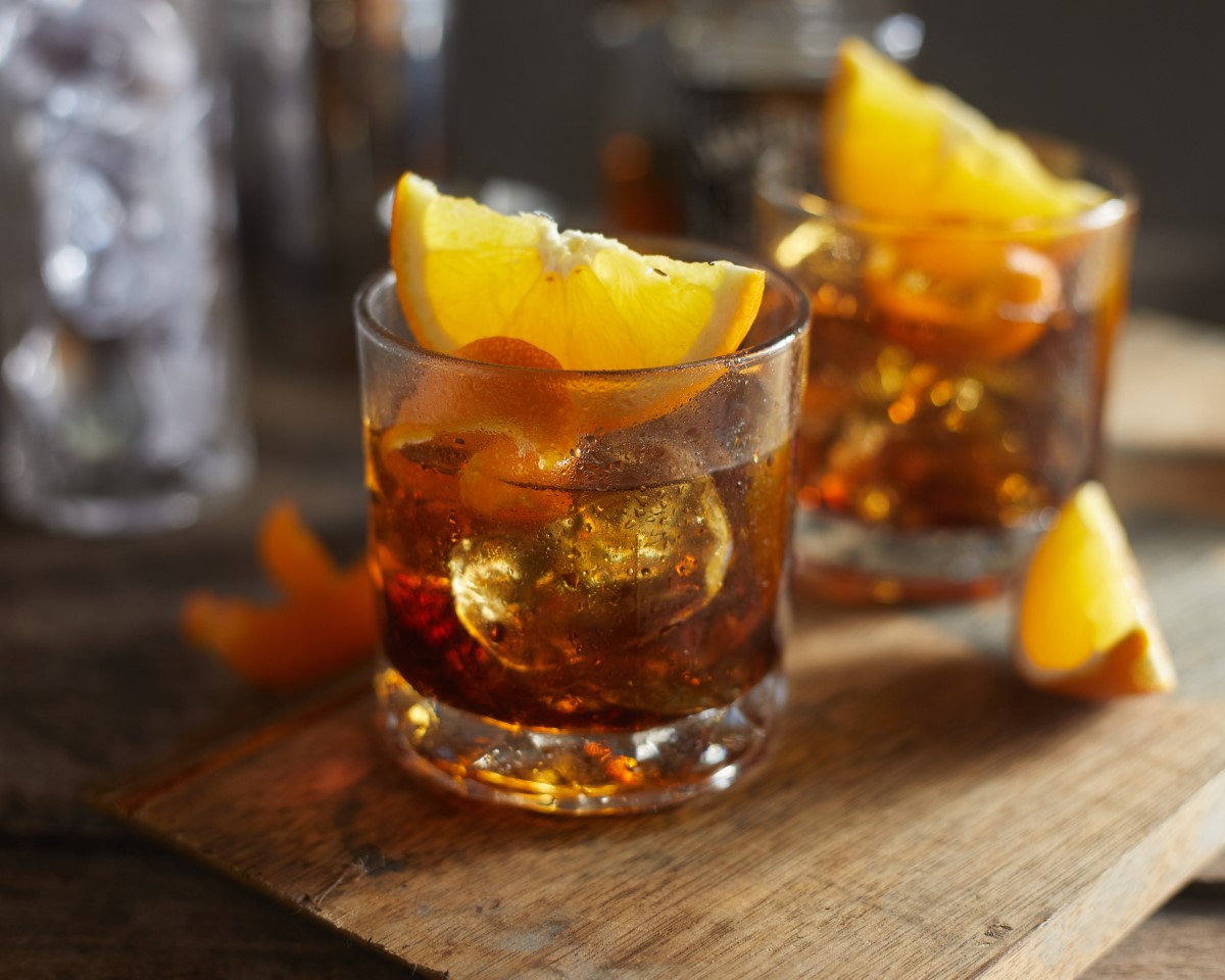 Glasses of dark cola with ice and yellow lemon wedges on wooden surface