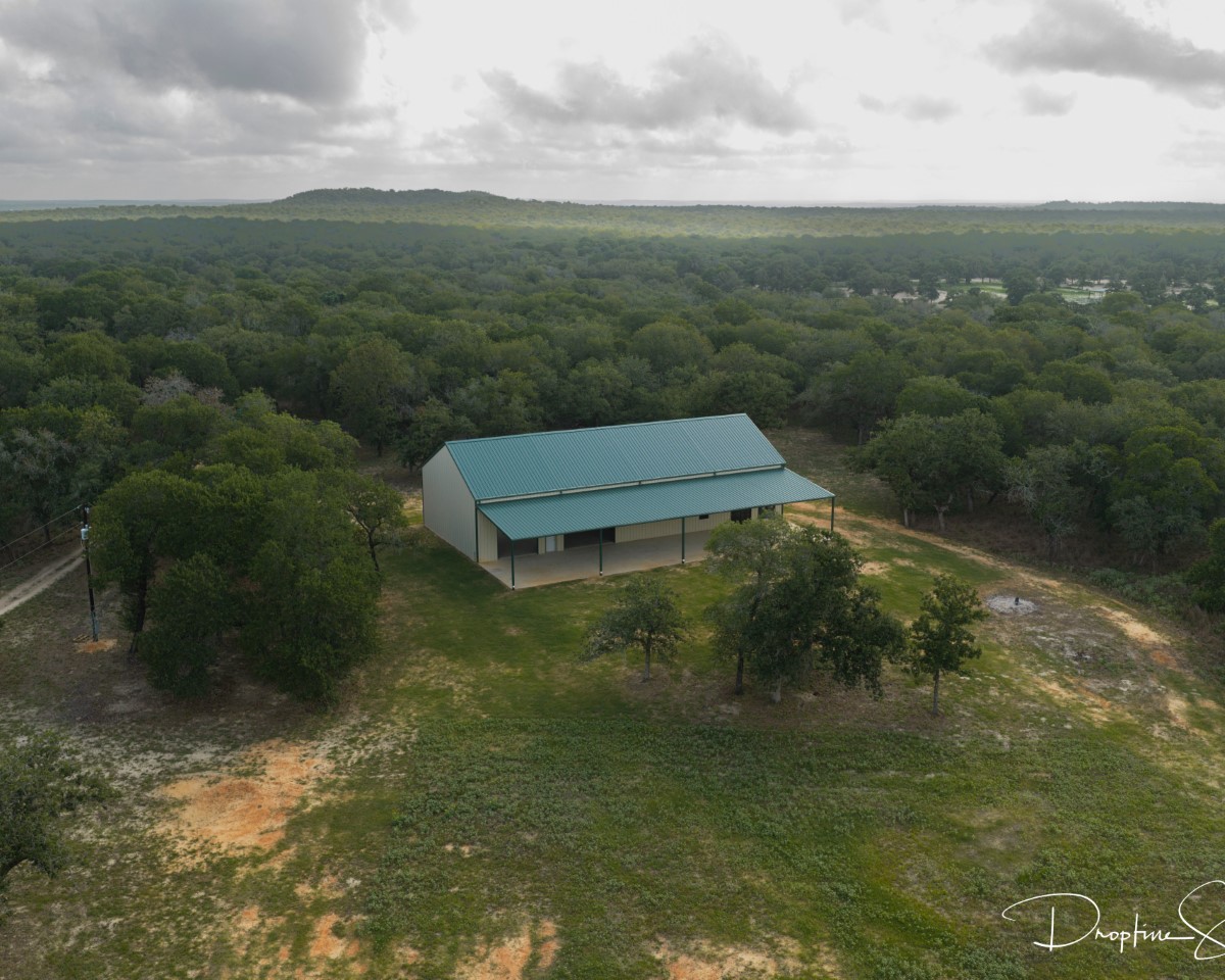 Modern ranch building with turquoise roof surrounded by trees, ideal tour location in countryside.