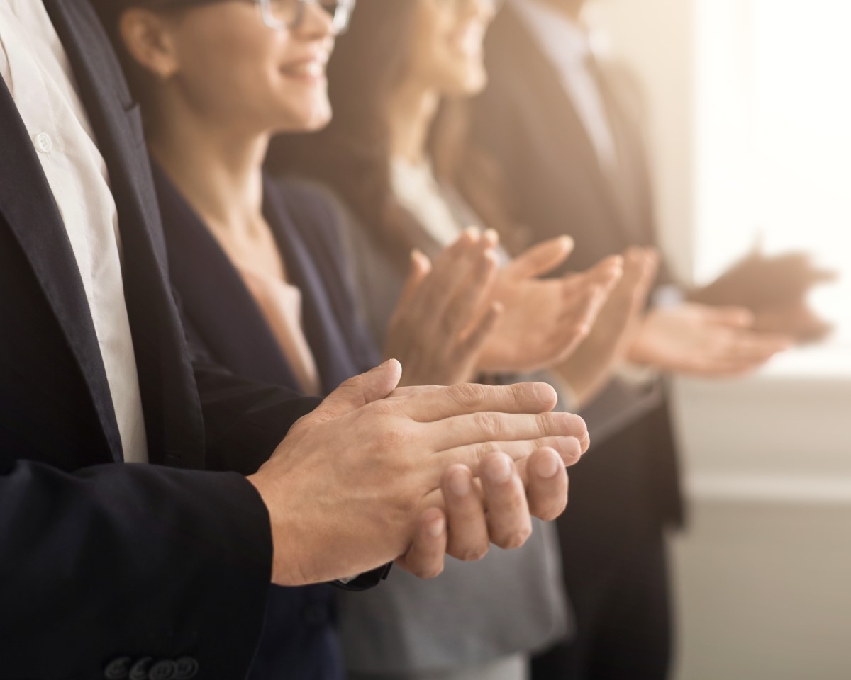 Business professionals clapping hands during corporate retreat teambuilding event