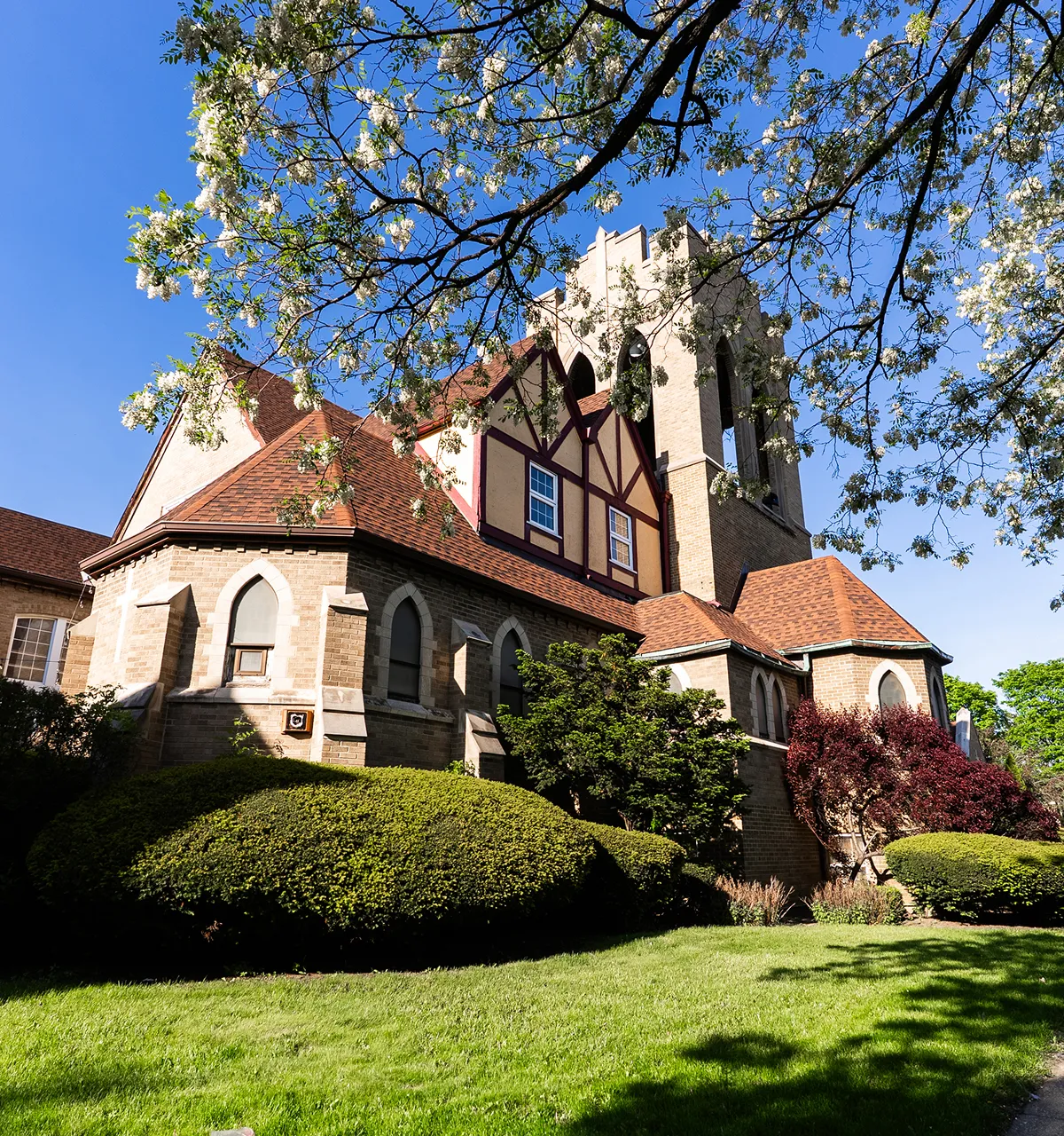A stone church building with arched windows and a tall bell tower under a clear blue sky.
