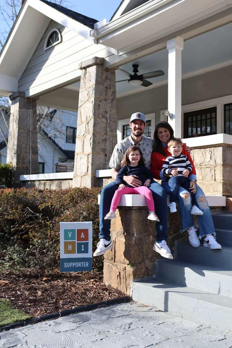 The Mehl family posing on the steps of their craftsman-style porch with a VAHI Supporter sign
