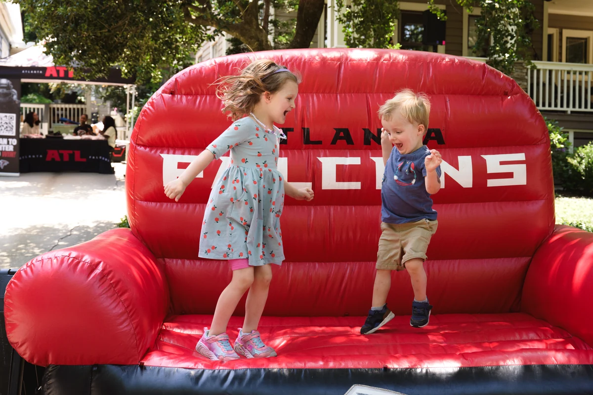 Two children jumping on a giant inflatable Atlanta Falcons couch at Porchfest.