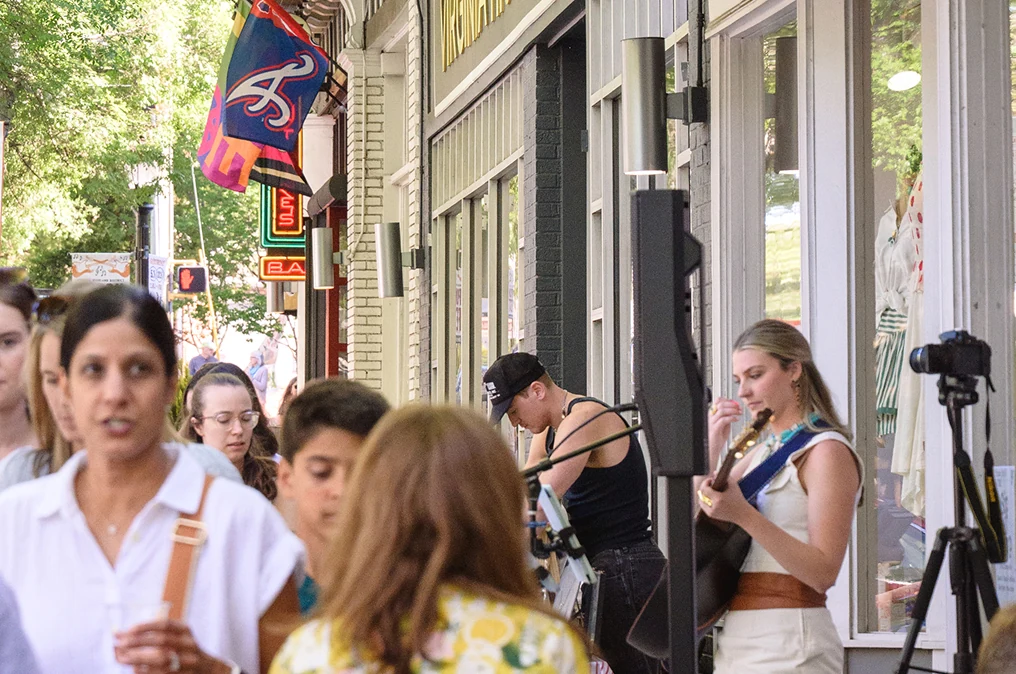Street musicians performing outside shops with pennant flags hanging overhead