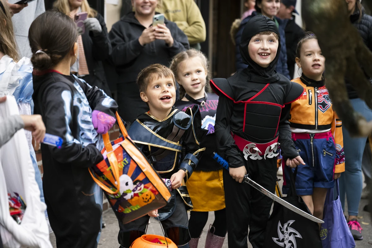 A group of children in ninja and superhero costumes trick-or-treat together during Candy Crawl.