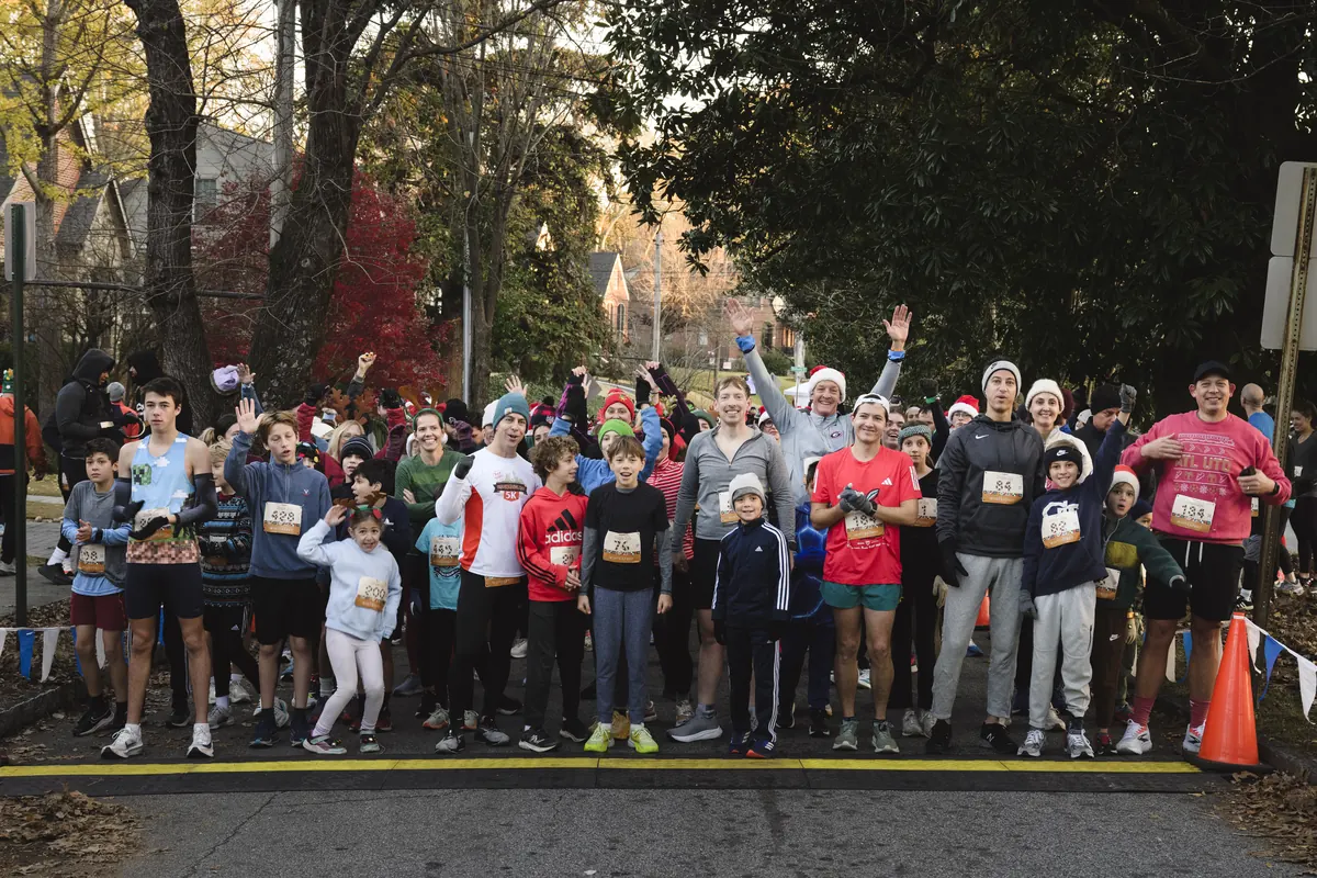 Group of runners posing together before the Winterfest Jingle Jog 5K, several wearing Santa hats.