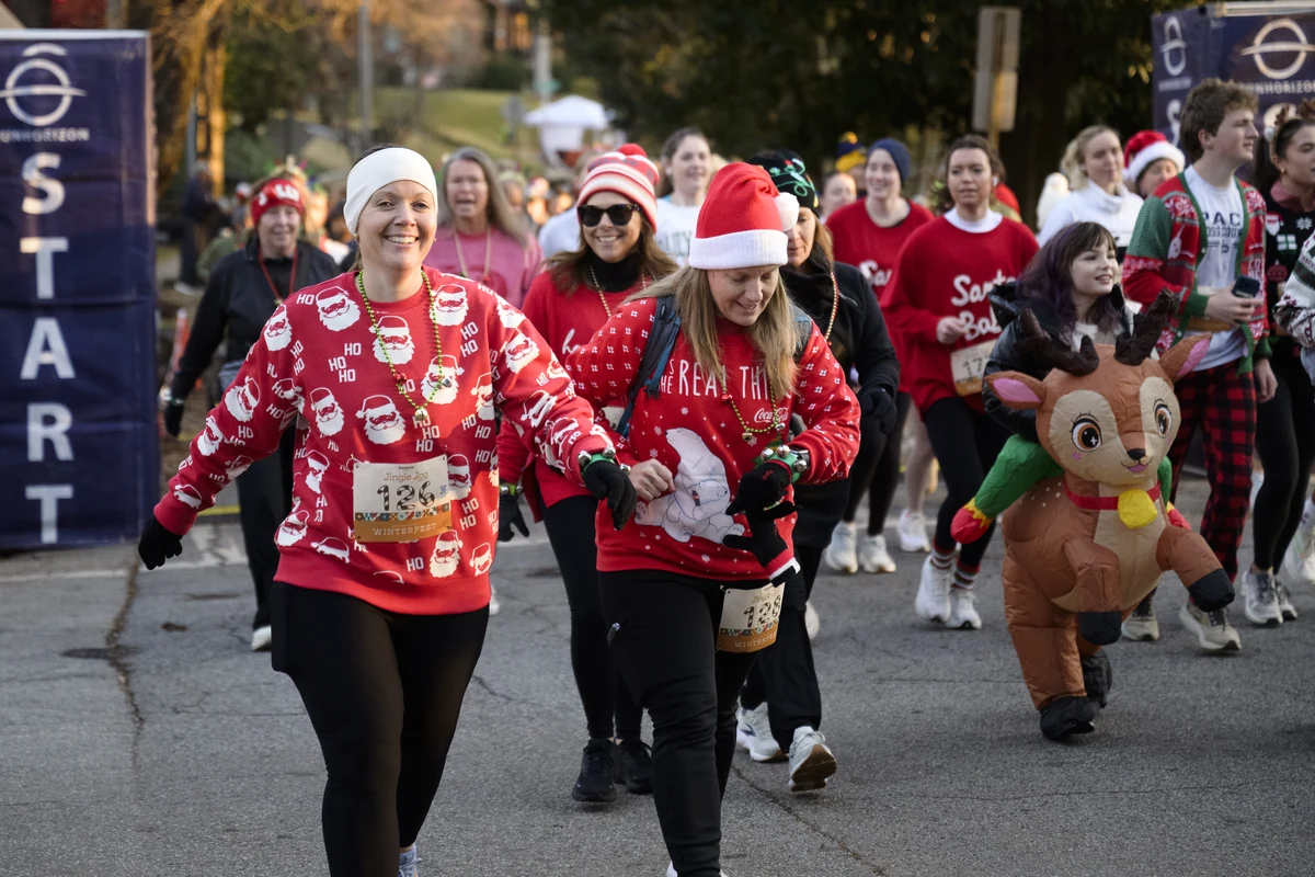 Runners in holiday sweaters and a reindeer costume near the start line of the Winterfest Jingle Jog 5K.