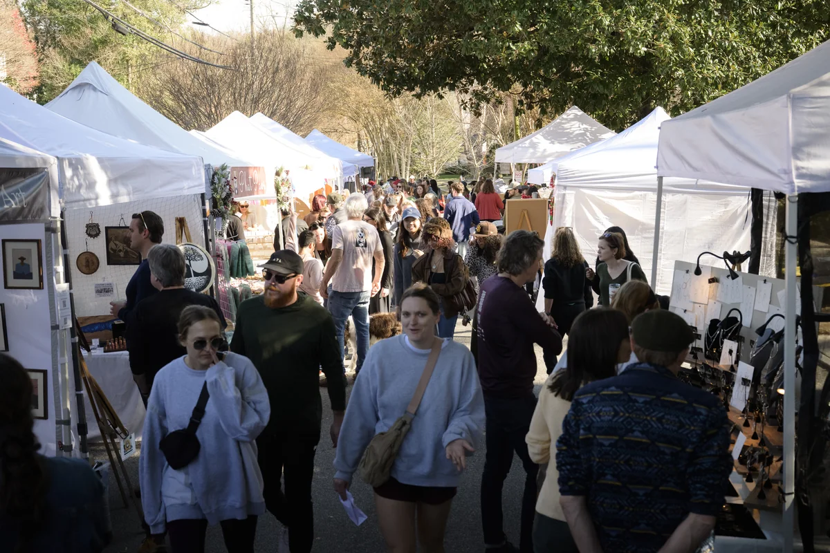 Crowds browsing a row of white vendor tents lining the street at Winterfest.