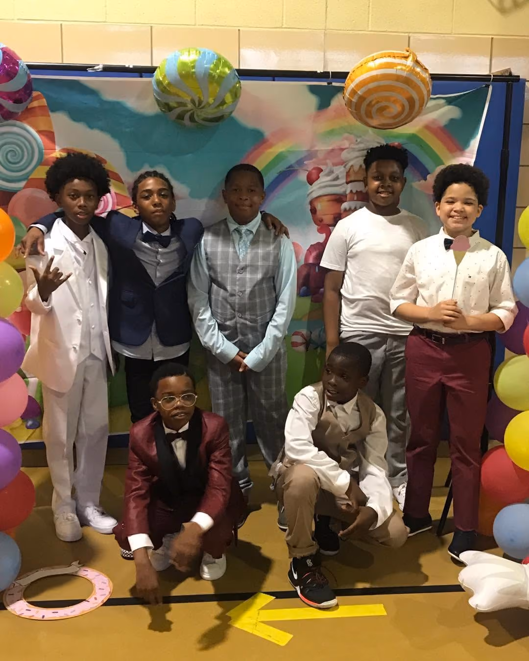 Seven students dressed up posing at a school dance photo booth
