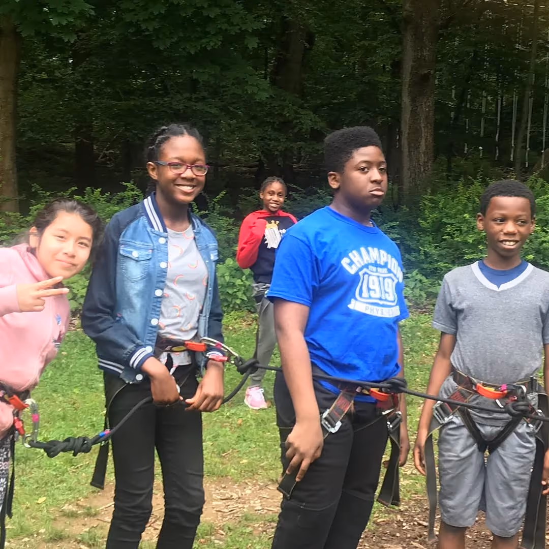 Students wearing climbing harnesses during an outdoor ropes course activity