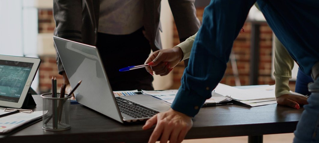 Team collaborating around a desk with laptops