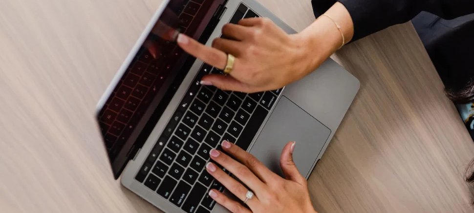 Hands typing on a laptop at a wooden desk