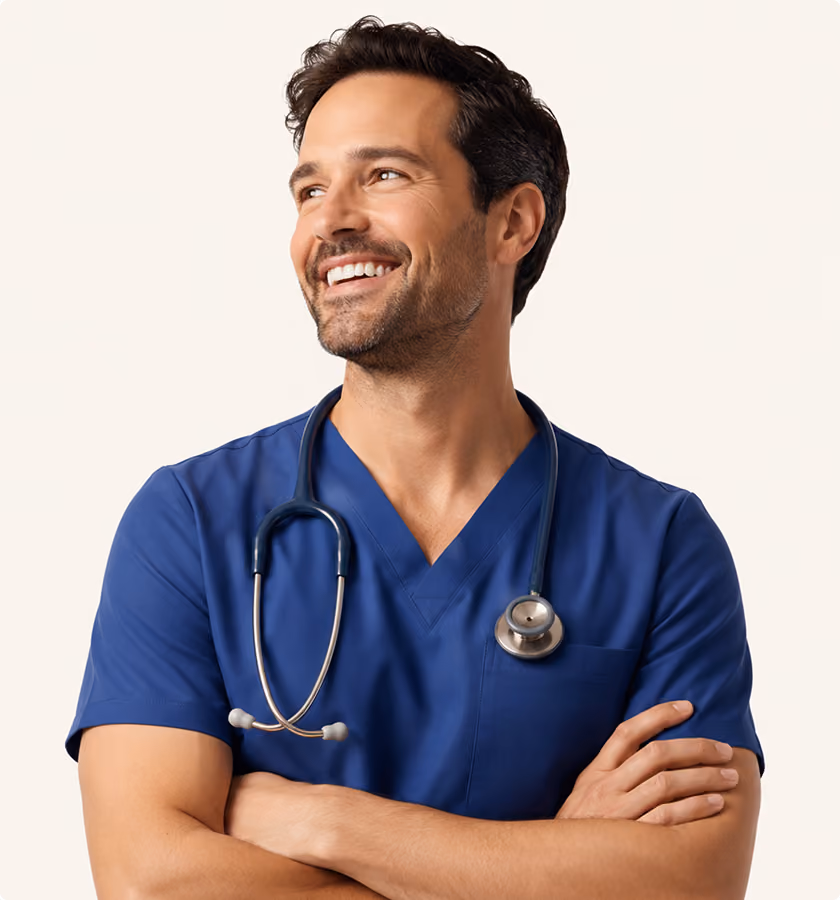 Smiling male healthcare worker in blue scrubs with stethoscope around neck and arms crossed.