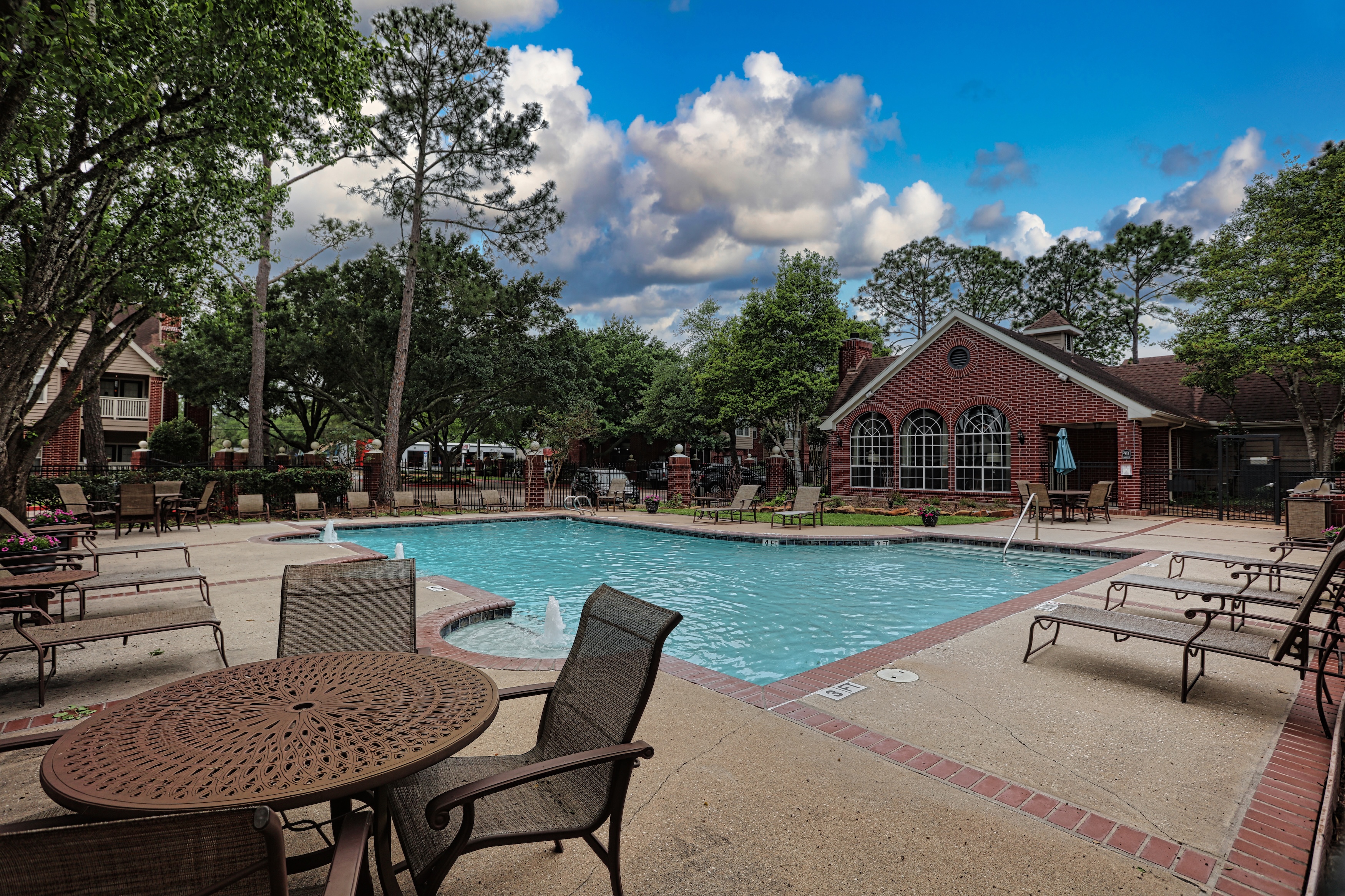 Pool with chairs and table and clubhouse in back