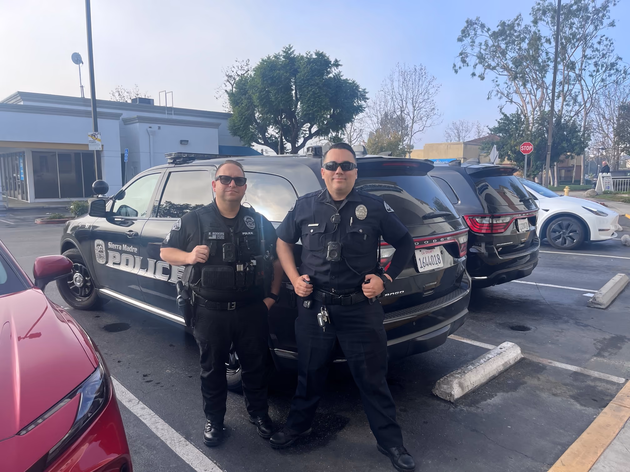 Two Sierra Madre Police officers standing beside a patrol vehicle in a parking lot